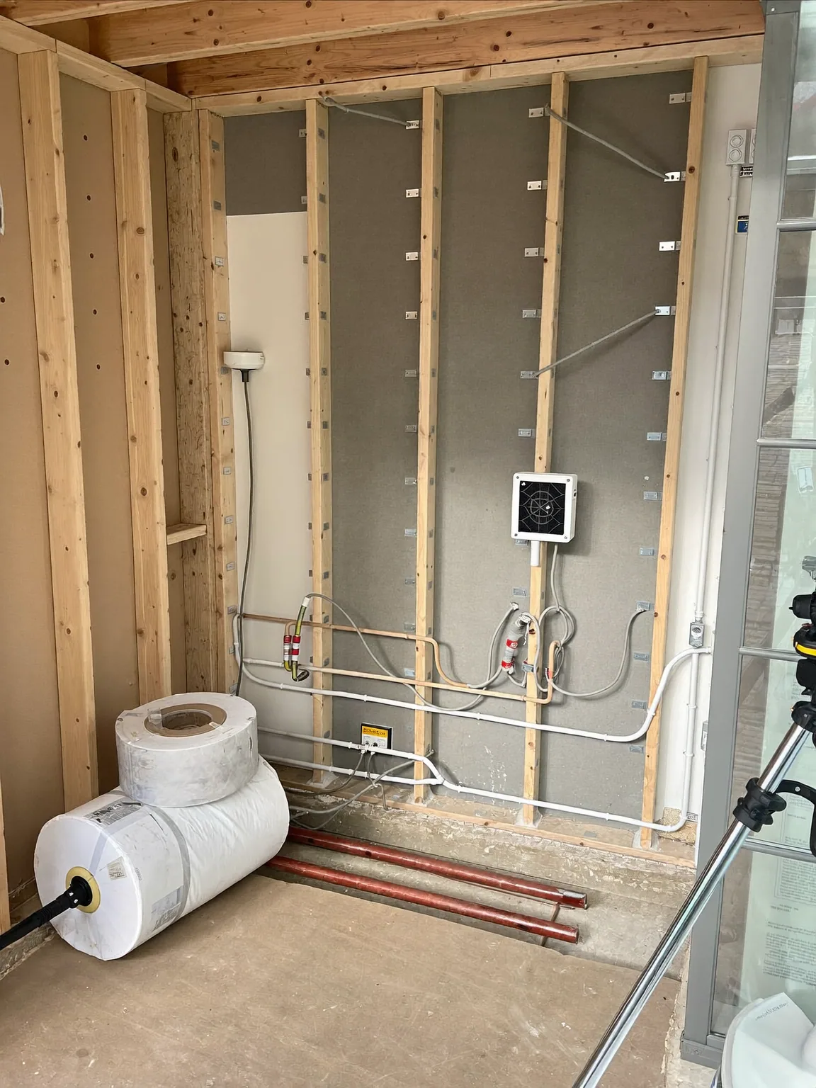Timber stud walls with first-fix electrical cabling and copper pipework before plastering