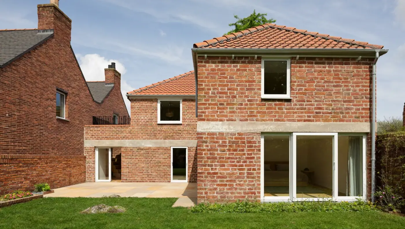 Two-storey red-brick rear extension with a clay-tiled roof and white-framed patio doors
