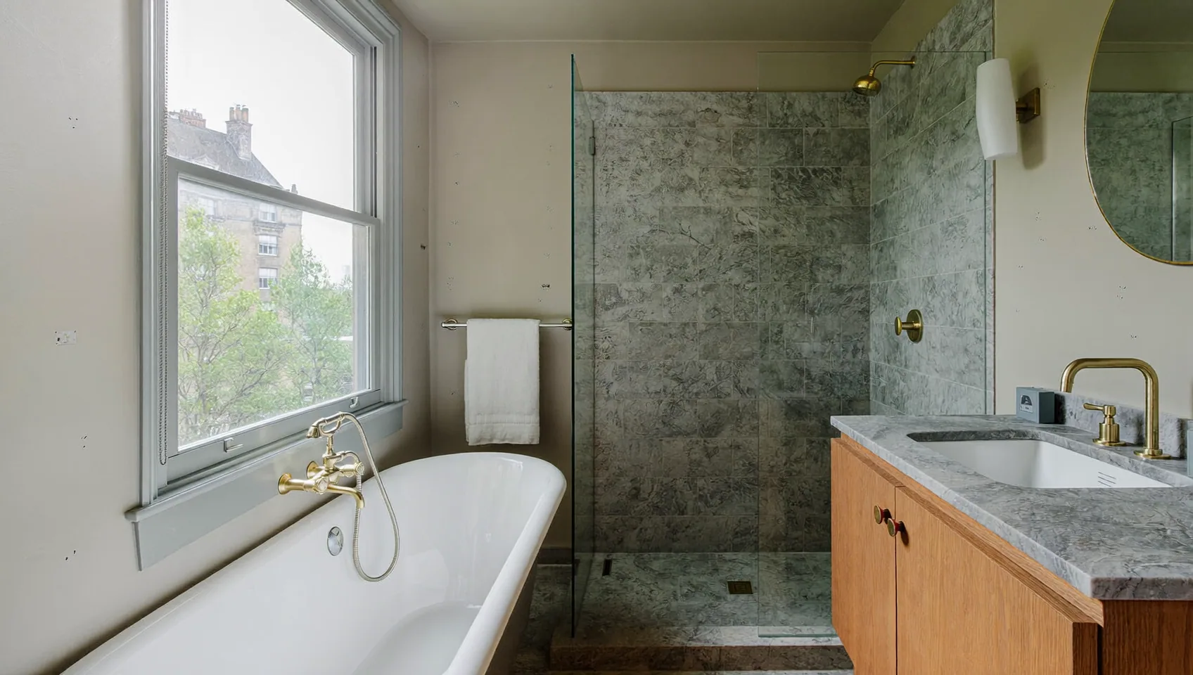 Bathroom with a freestanding bath, brass taps, a walk-in shower with stone-effect tiles and a sash window